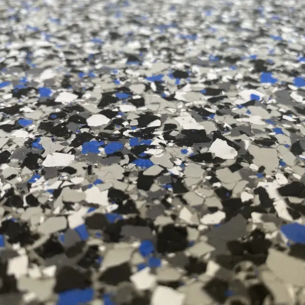Close-up view of a speckled epoxy floor with blue, black, and gray fragments interspersed, creating a textured and colorful surface pattern.