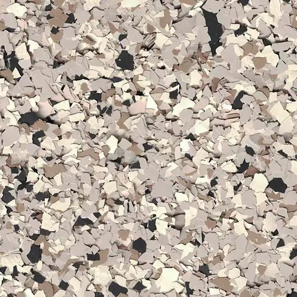 The image shows a surface covered in fragmented, irregularly shaped multicolored flakes, creating a textured, abstract pattern with shades of beige, brown, and black.