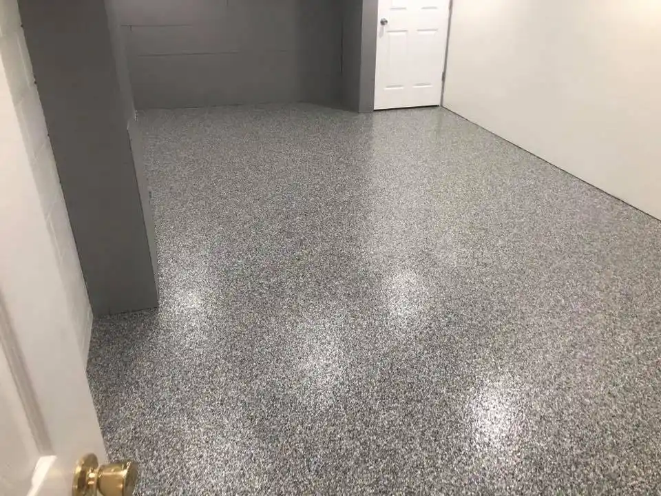 Empty room with speckled gray polished floor, white walls, and a closed white door. Modern, minimalist interior design with no visible furniture.